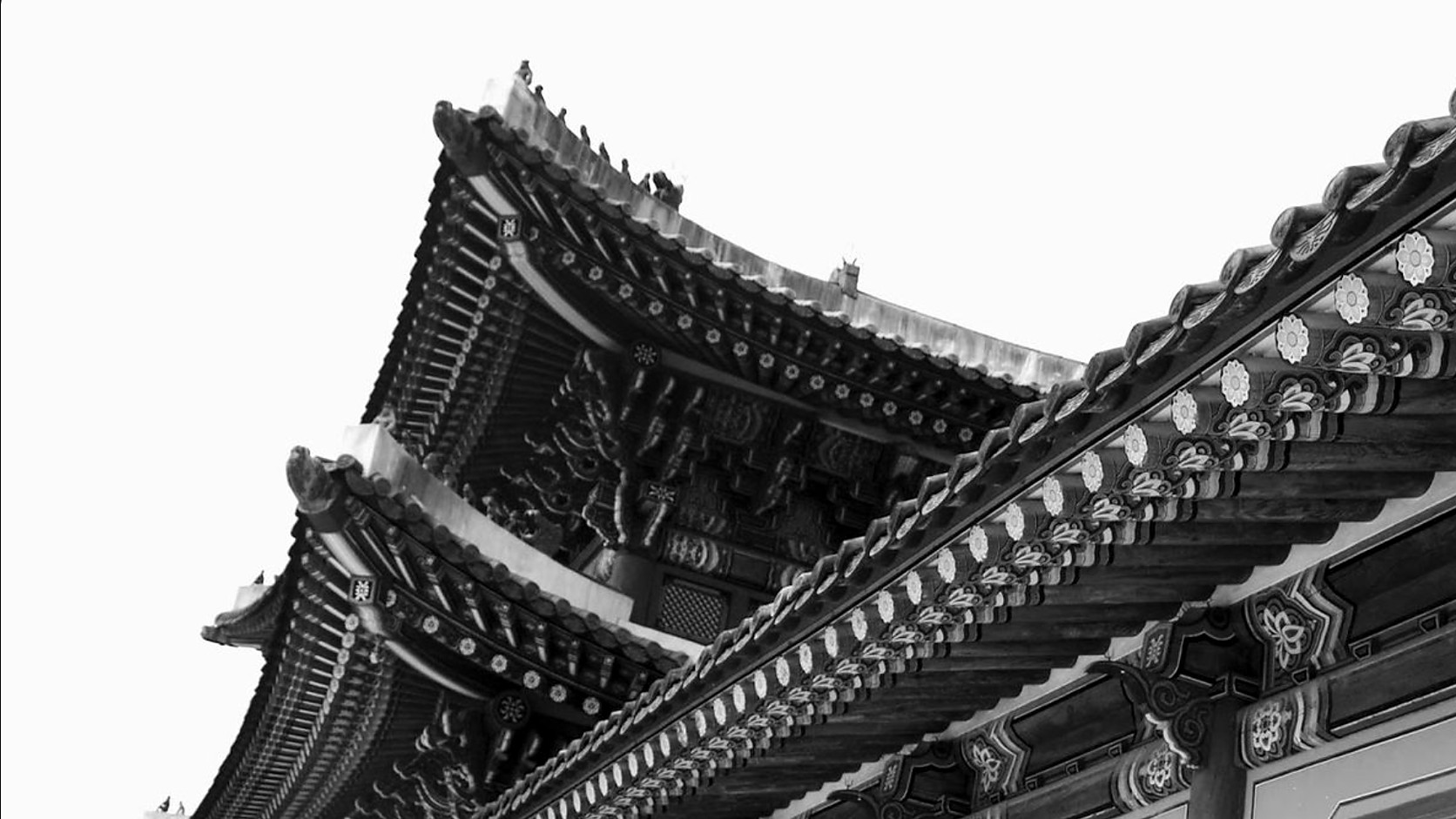 The tiered eaves of a traditional Chinese roof with carved brackets, in black and white