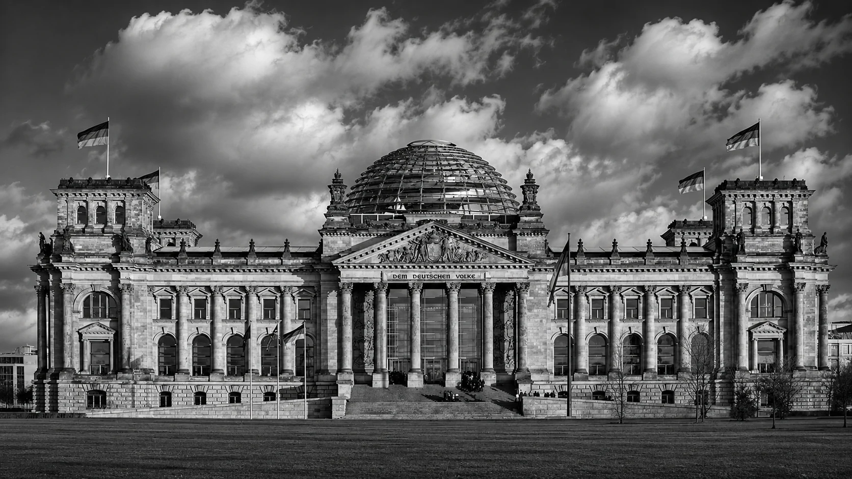 Black-and-white façade of the Reichstag in Berlin with German flags