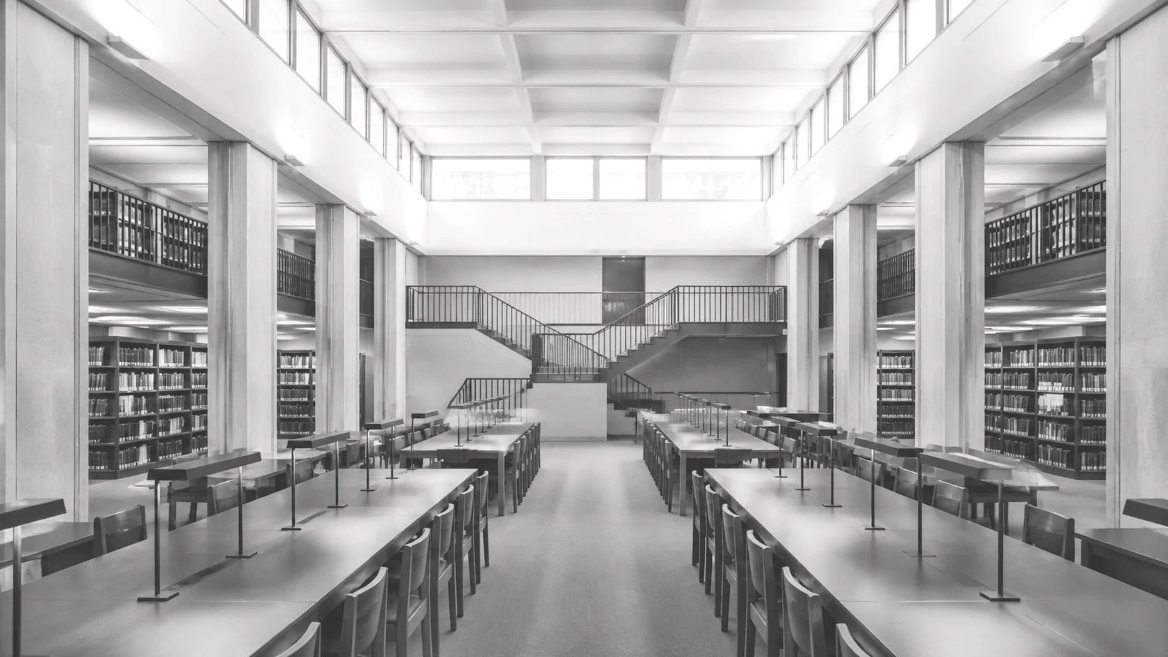 A two-storey library reading room with long tables and book stacks
